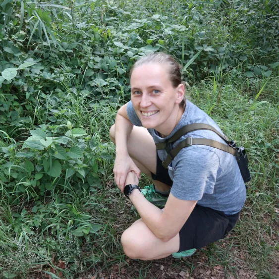 Hanneke als natuurgids van IVN, gehurkt in het groen