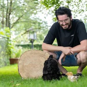 Doron van Bijdemaker in het gras naast een boomschijf en zijn hond