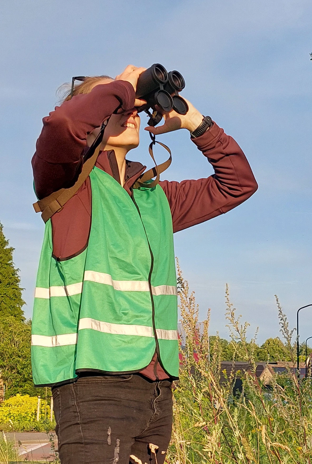 Hanneke kijkt met een verrekijker de lucht in